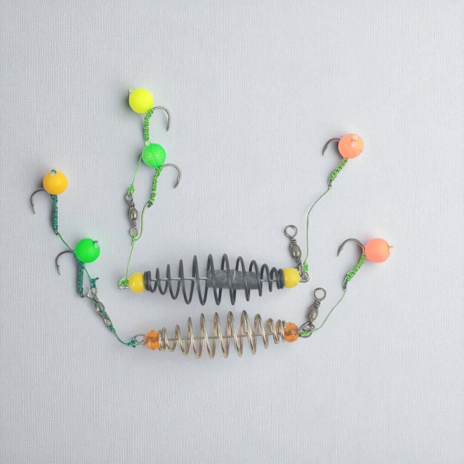 Metal coil fishing feeder rig equipped with three hooks and colorful floating bait balls, ideal for bottom fishing and attracting big fish.
