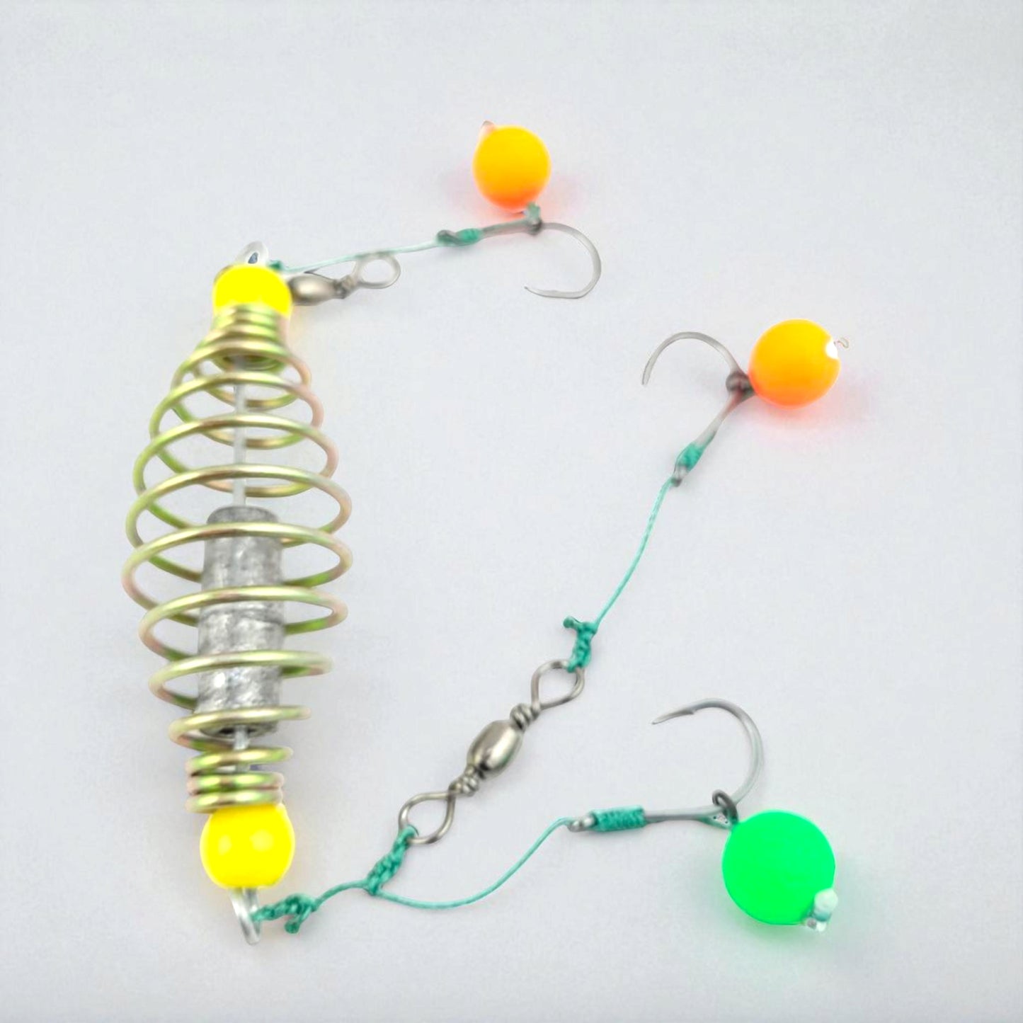 Carp fishing spring feeder rig featuring a metal coil feeder and three baited hooks tied with green fishing line, designed for groundbait fishing.