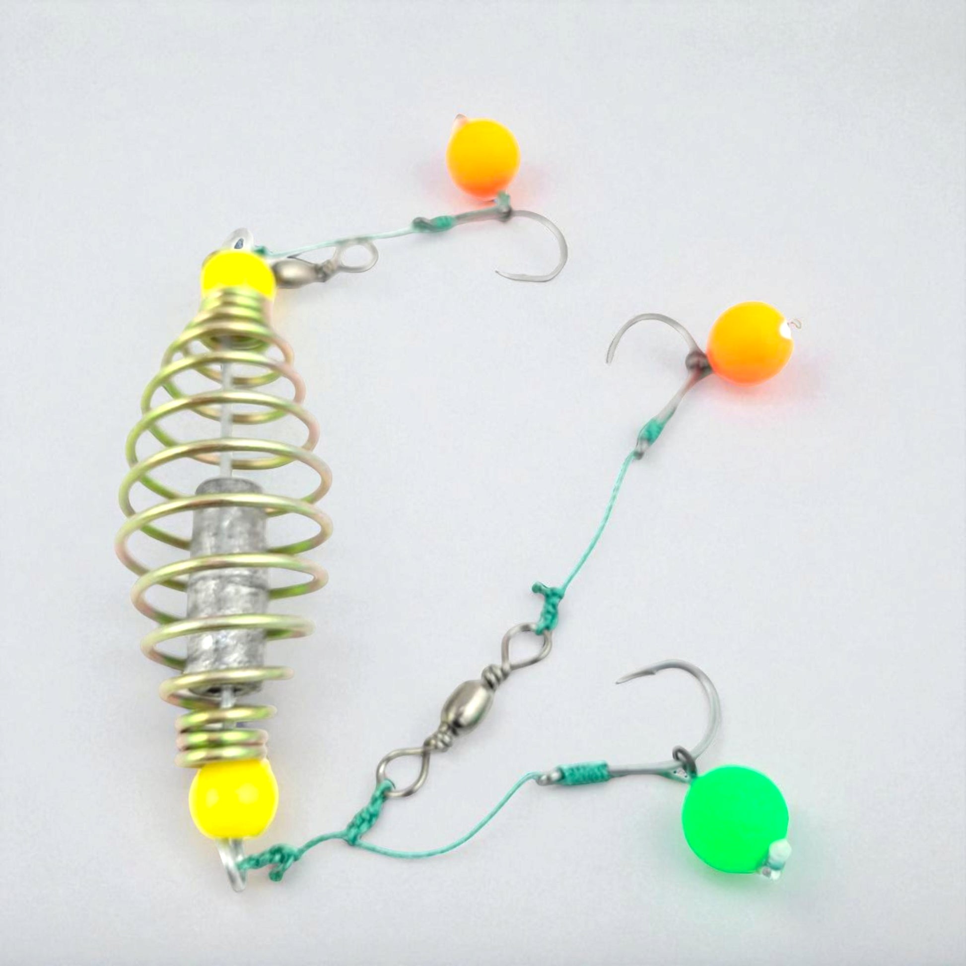 Carp fishing spring feeder rig featuring a metal coil feeder and three baited hooks tied with green fishing line, designed for groundbait fishing.