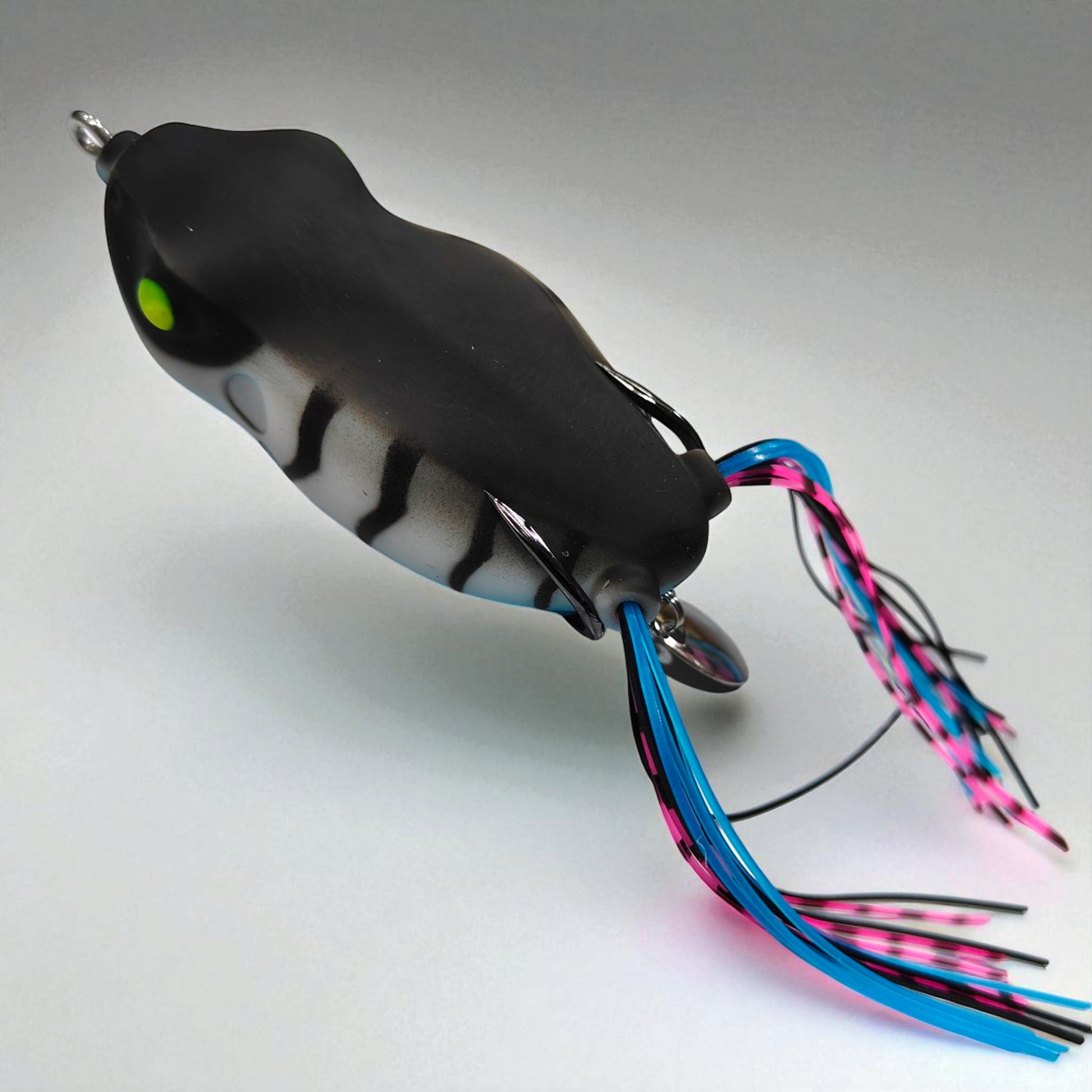 Soft hollow-body frog bait with silicone skirt legs and hidden steel hooks – ideal for weedless surface fishing in shallow waters

