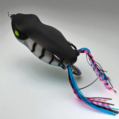 Soft hollow-body frog bait with silicone skirt legs and hidden steel hooks – ideal for weedless surface fishing in shallow waters
